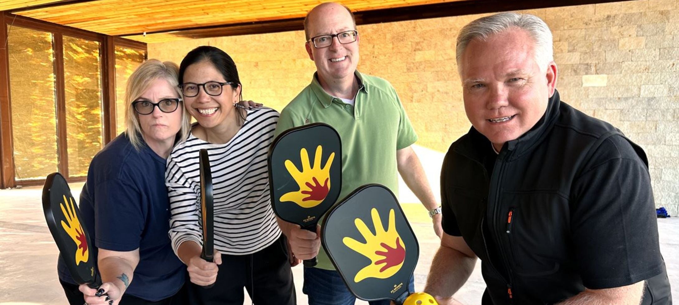 group of people holding custom black and yellow pickleball paddles